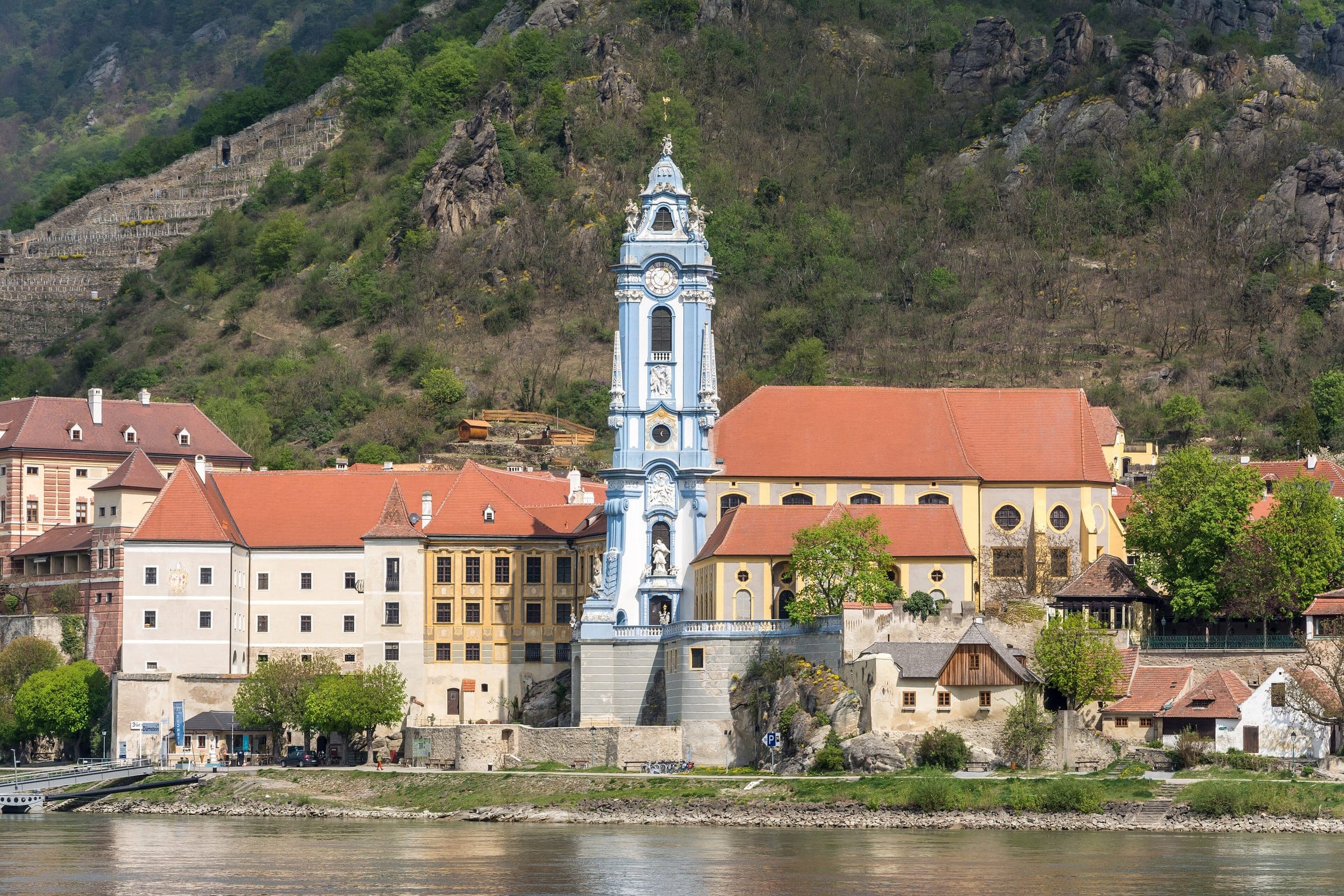The blue and white Baroque tower of Durnstein Abbey church rises above red roofs in the Wachau.