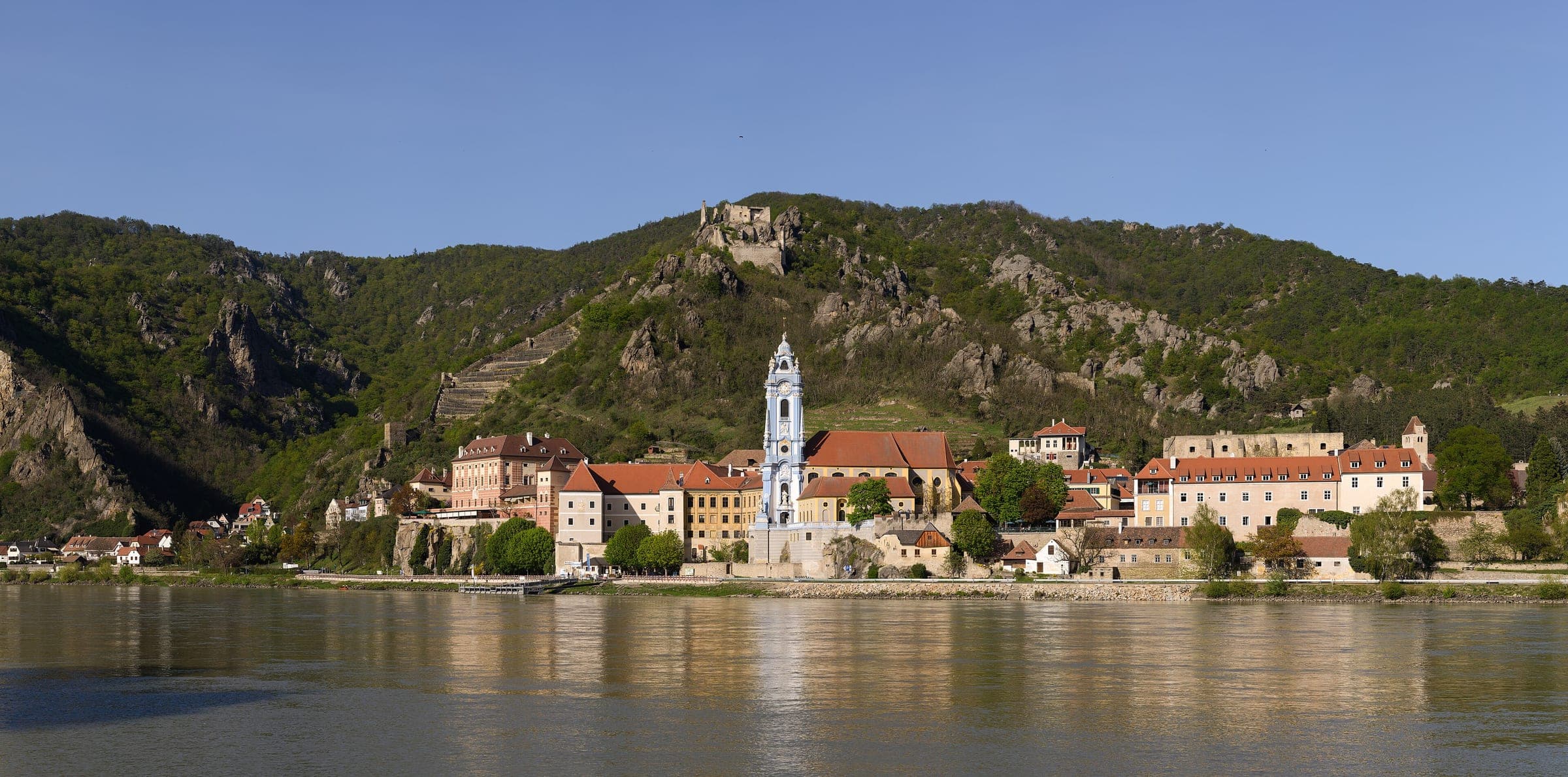 Durnstein lines the Danube bank below its castle ruin, with the blue and white abbey tower at its centre.