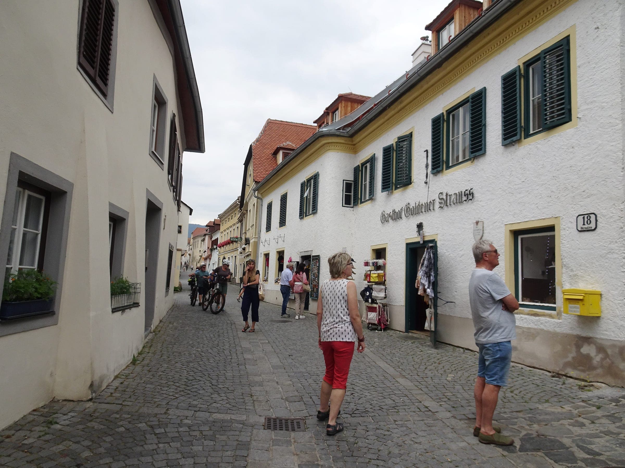 Walkers pass whitewashed houses on the narrow cobbled Hauptstrasse in Durnstein.