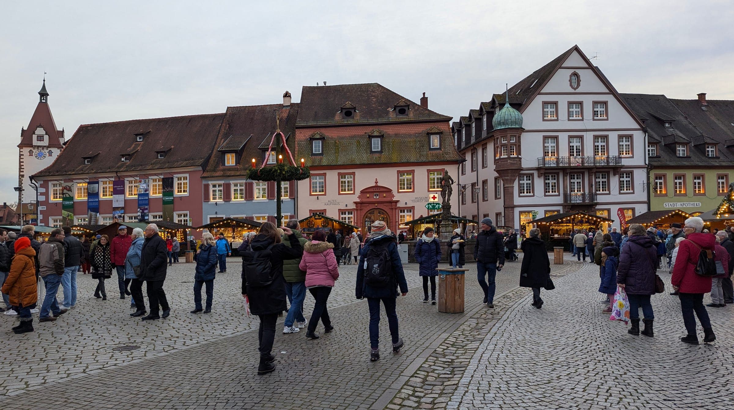 Shoppers cross Gengenbach's Rathausplatz past baroque and timber-framed houses on an overcast Advent day.