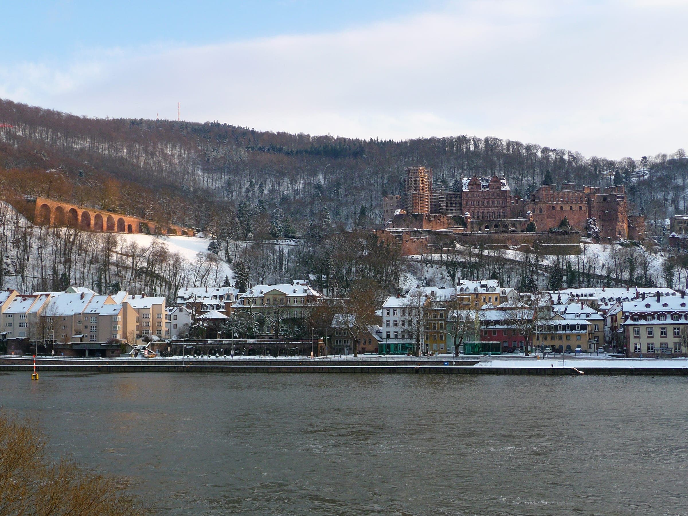 Snow dusts the roofs below Heidelberg Castle seen across the Neckar on a winter afternoon.