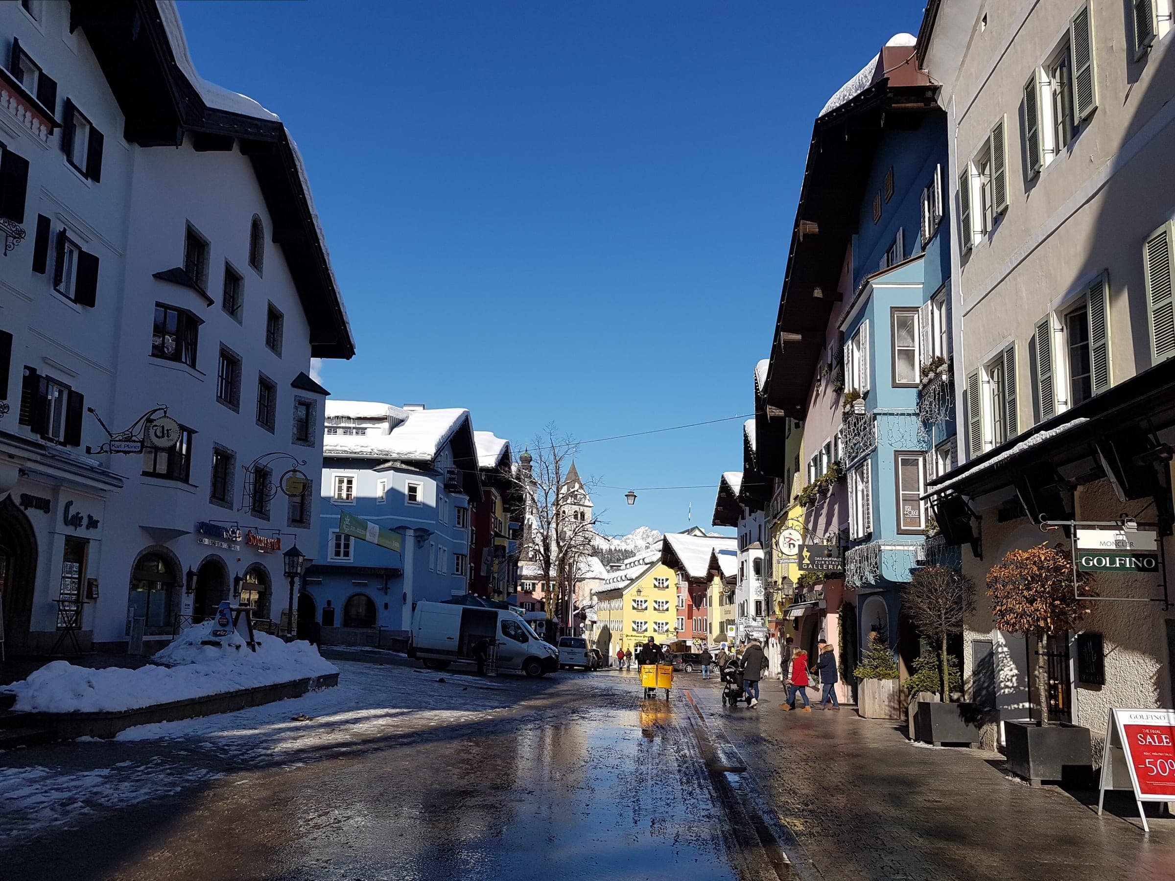 Snow lines the eaves of the painted townhouses along Kitzbühel's Vorderstadt under a clear winter sky.
