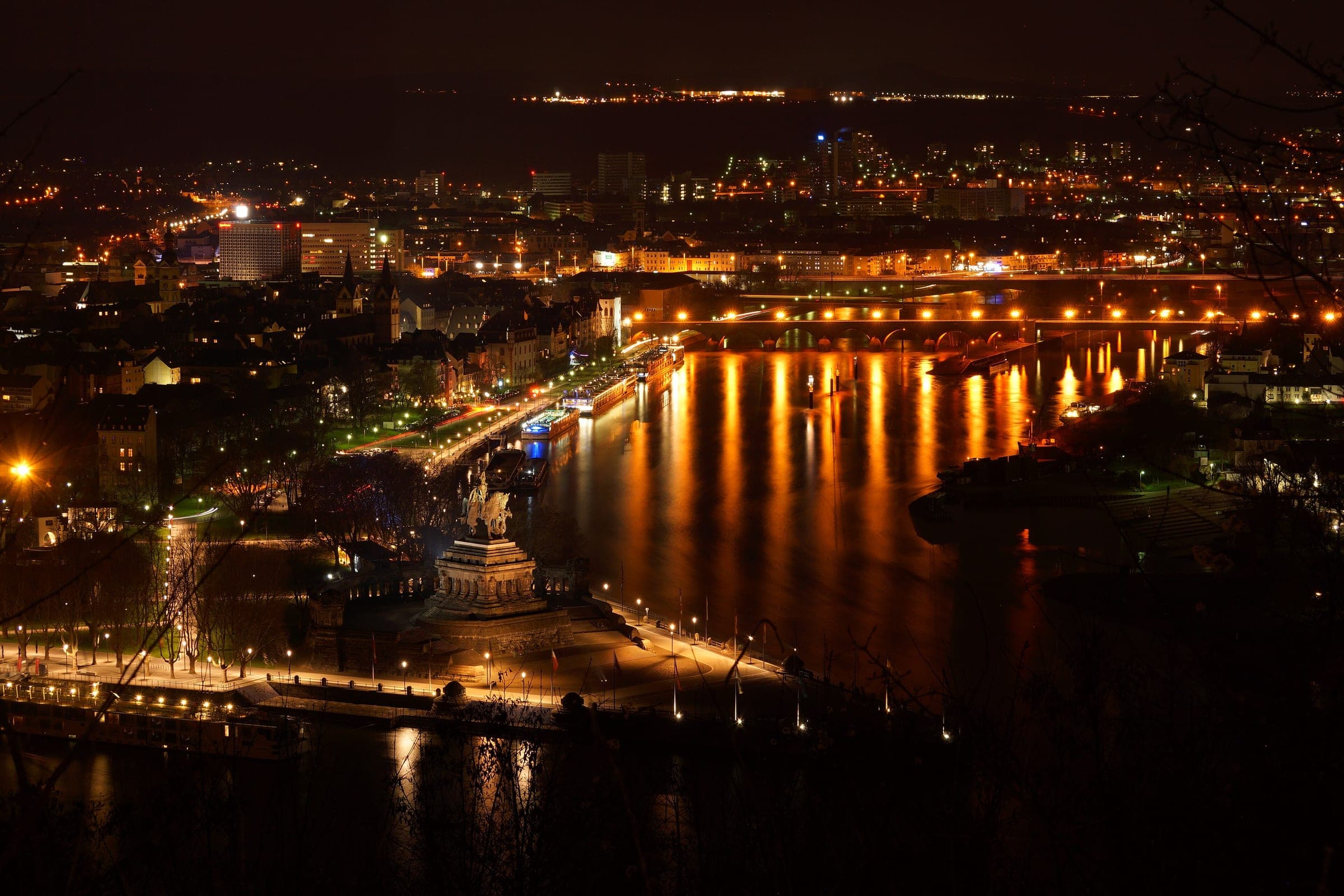The Deutsches Eck and the lit Rhine and Moselle banks of Koblenz spread out below at night