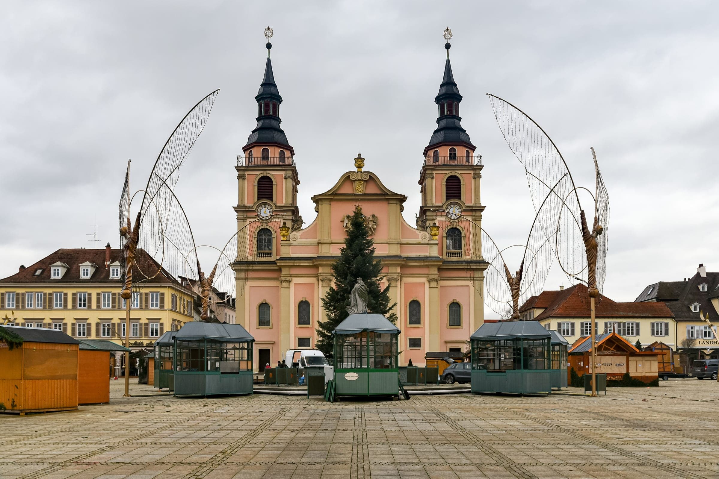 Wire angels and closed market kiosks stand on Ludwigsburg's Marktplatz before the Stadtkirche on a grey day.