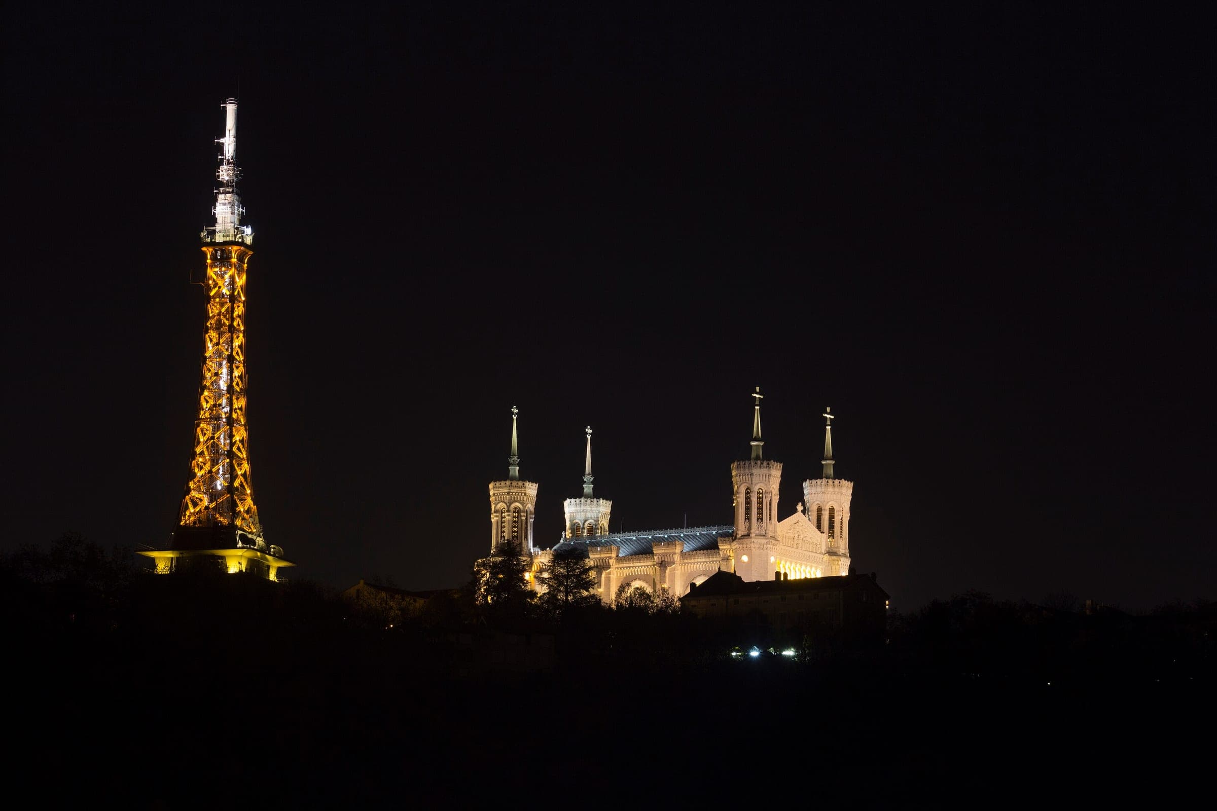 Fourvière basilica and the lit metal tower crown the dark hill above Lyon on a November night.