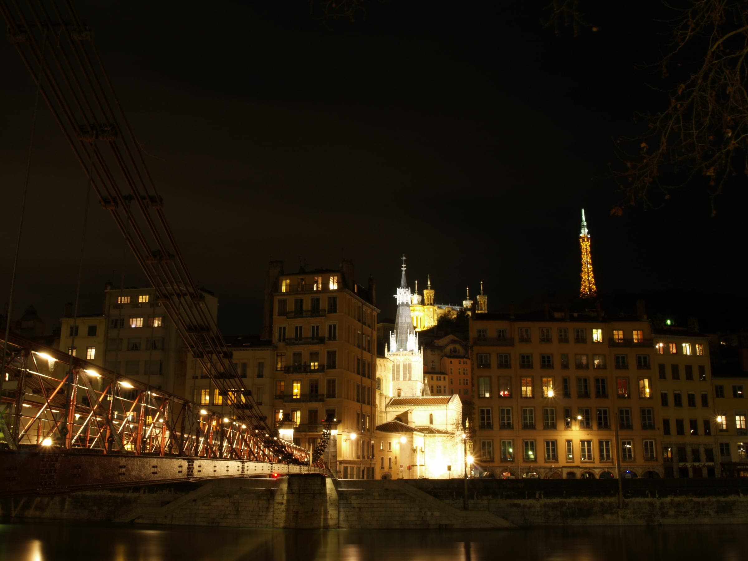 The Passerelle Saint-Vincent crosses the Saône toward lit Vieux Lyon facades and Fourvière on a December night.