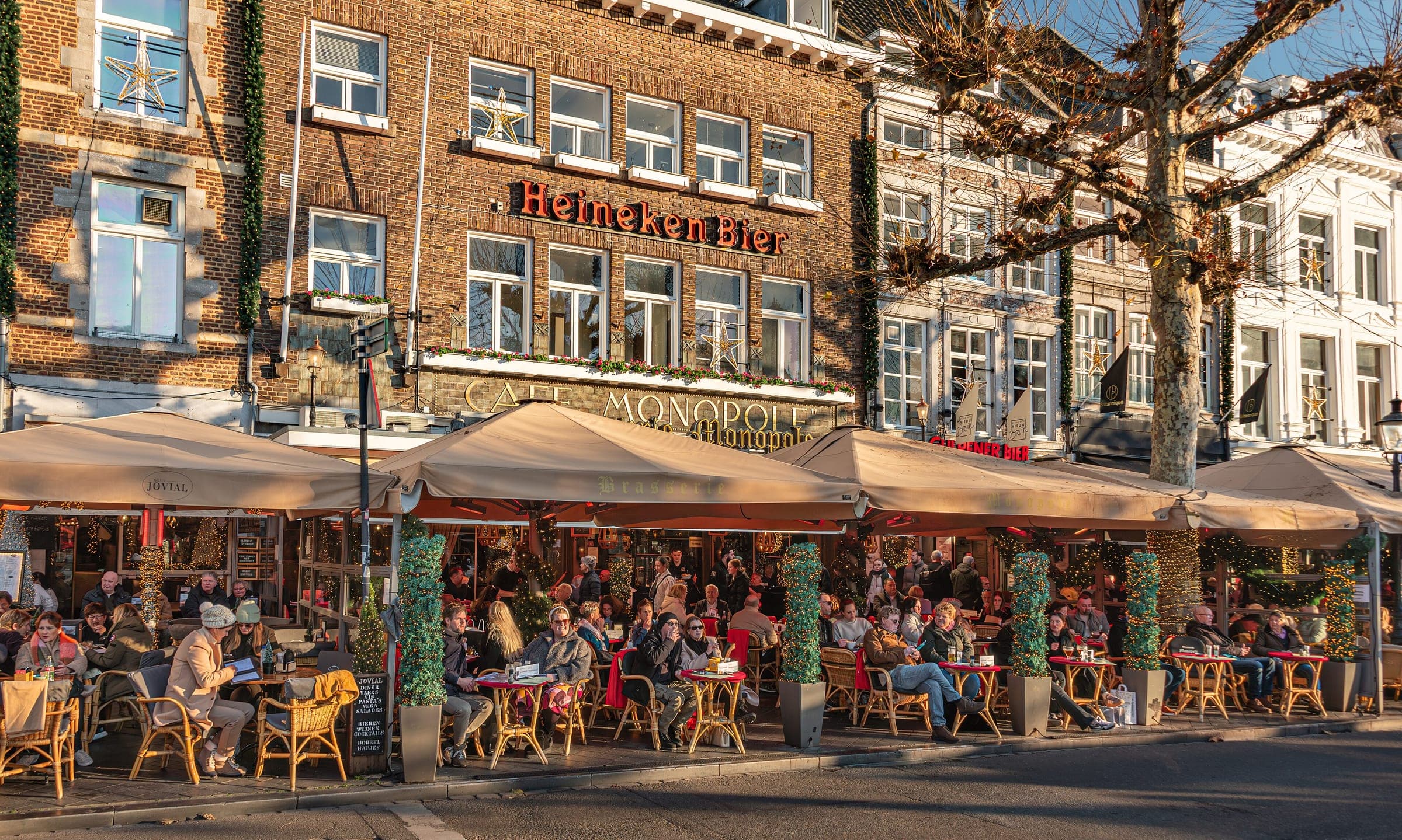 People sit out on the café terraces along the Vrijthof in Maastricht on a sunny winter afternoon.