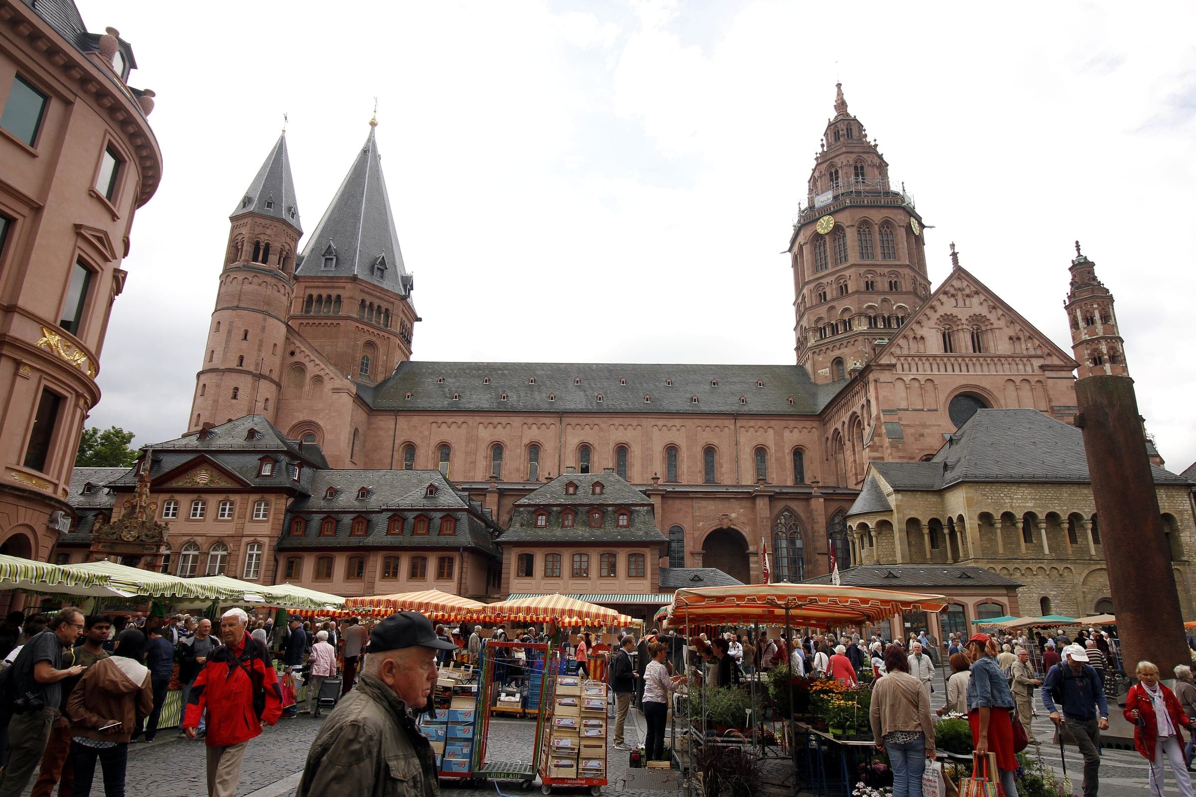 Market umbrellas fill the Markt in Mainz below the red sandstone towers of the cathedral.