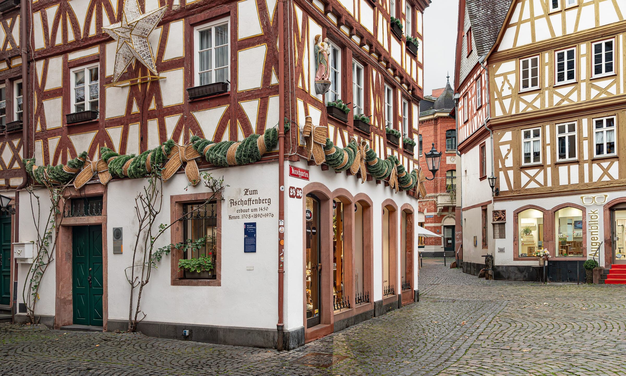 Garlands and stars hang on the timber-framed houses of the Kirschgarten in Mainz on a grey day.