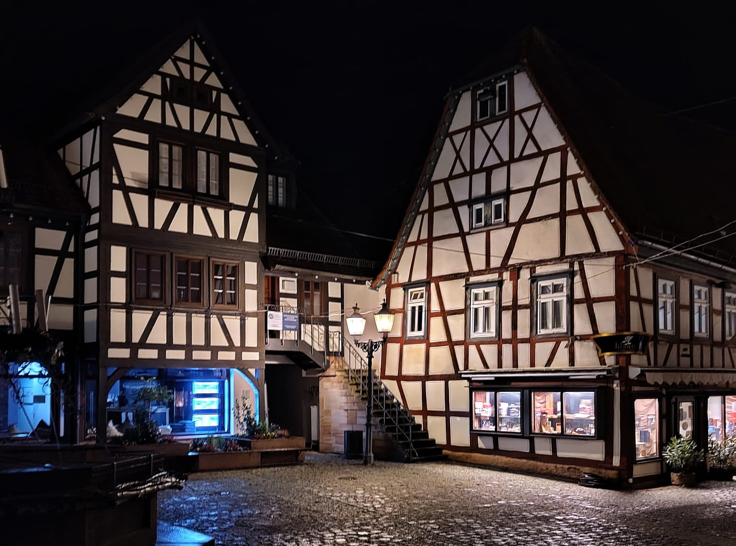 Street lamps light the timber-framed houses and cobbles of Michelstadt's Marktplatz on a November evening.