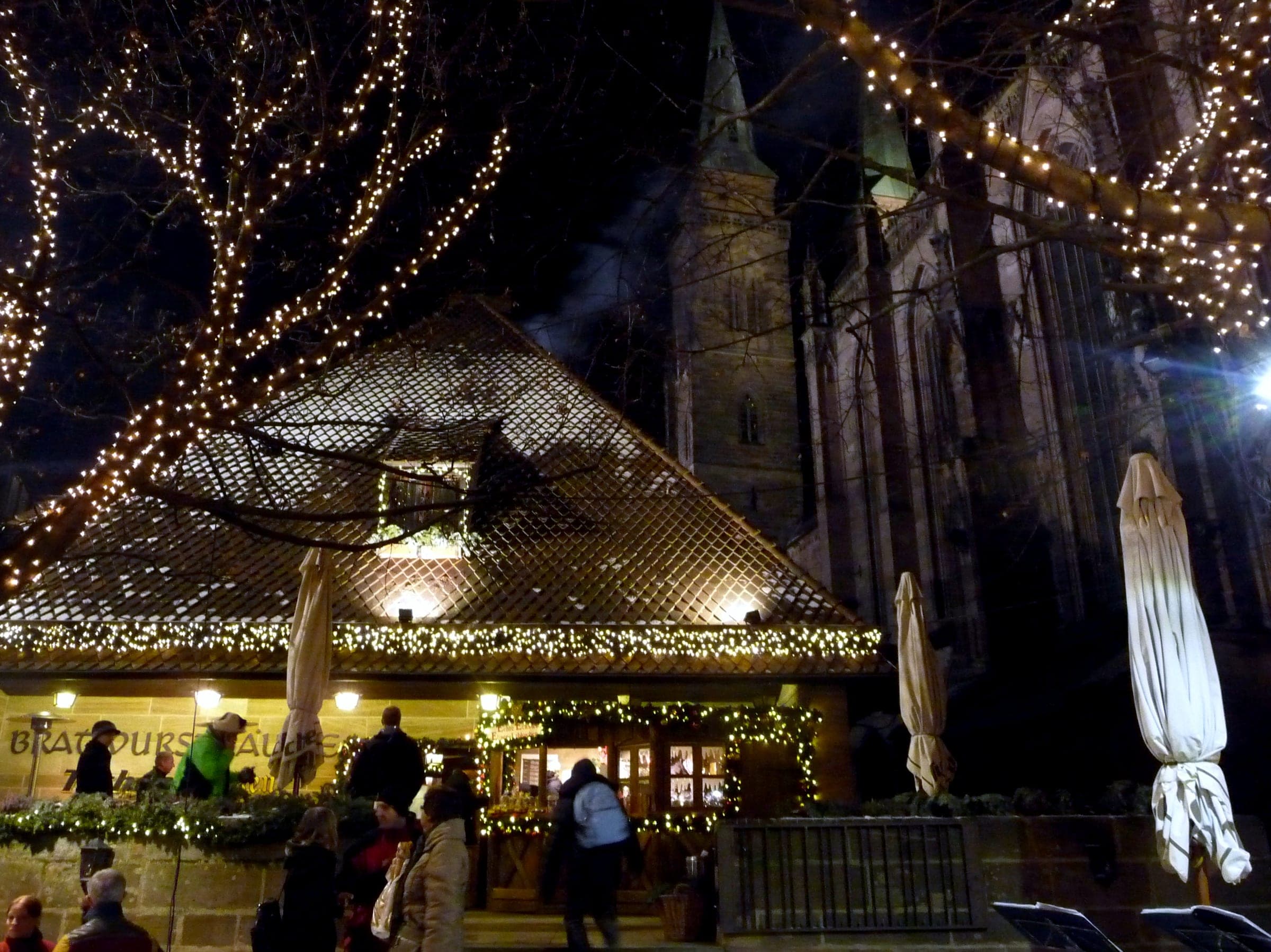 Lights wind through the trees outside the Bratwursthäusle beside St. Sebald's Church in Nuremberg on a winter night