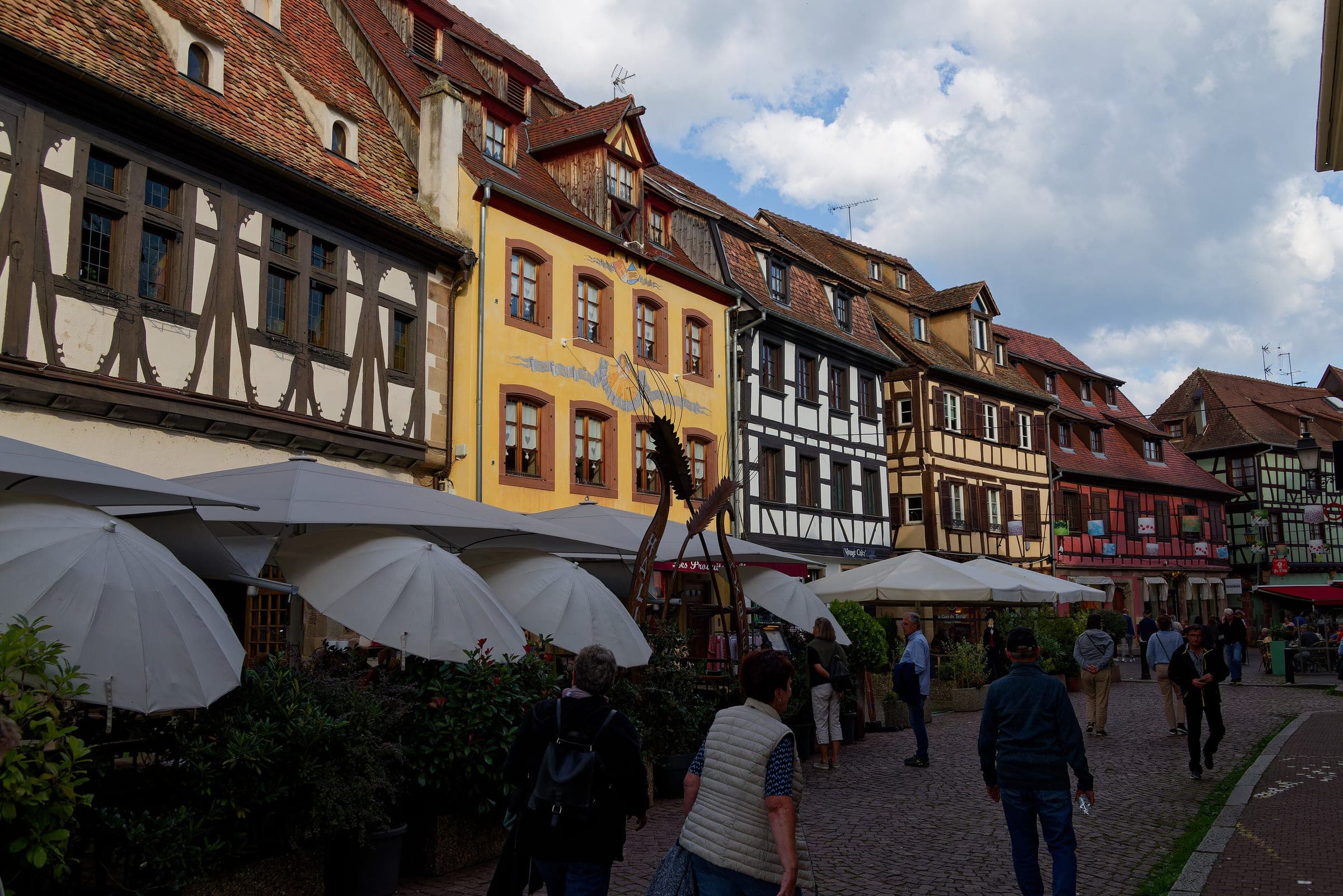 Café umbrellas line a street of tall half-timbered houses in the centre of Obernai.