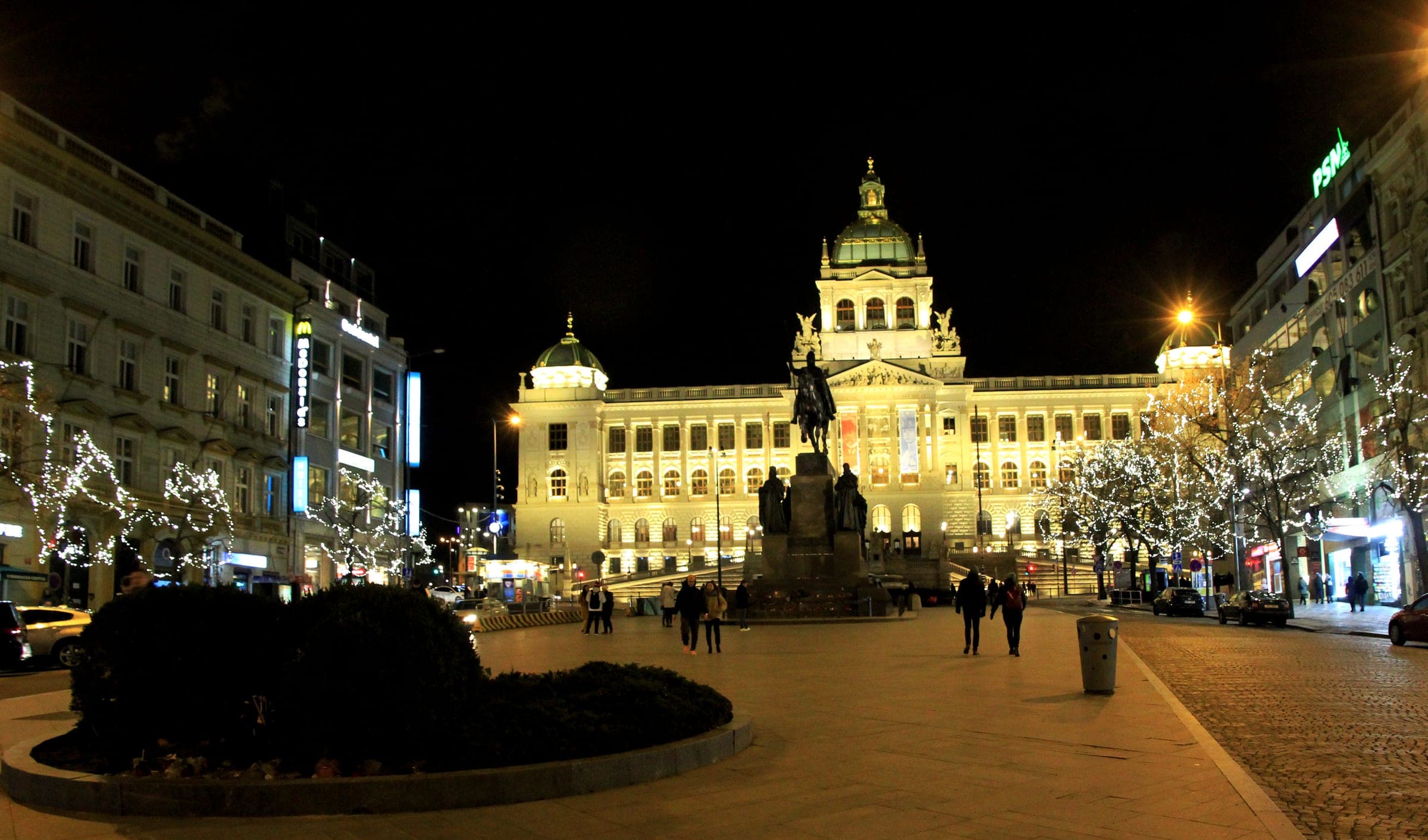 Christmas lights hang in the trees on Wenceslas Square as the National Museum glows at the top.