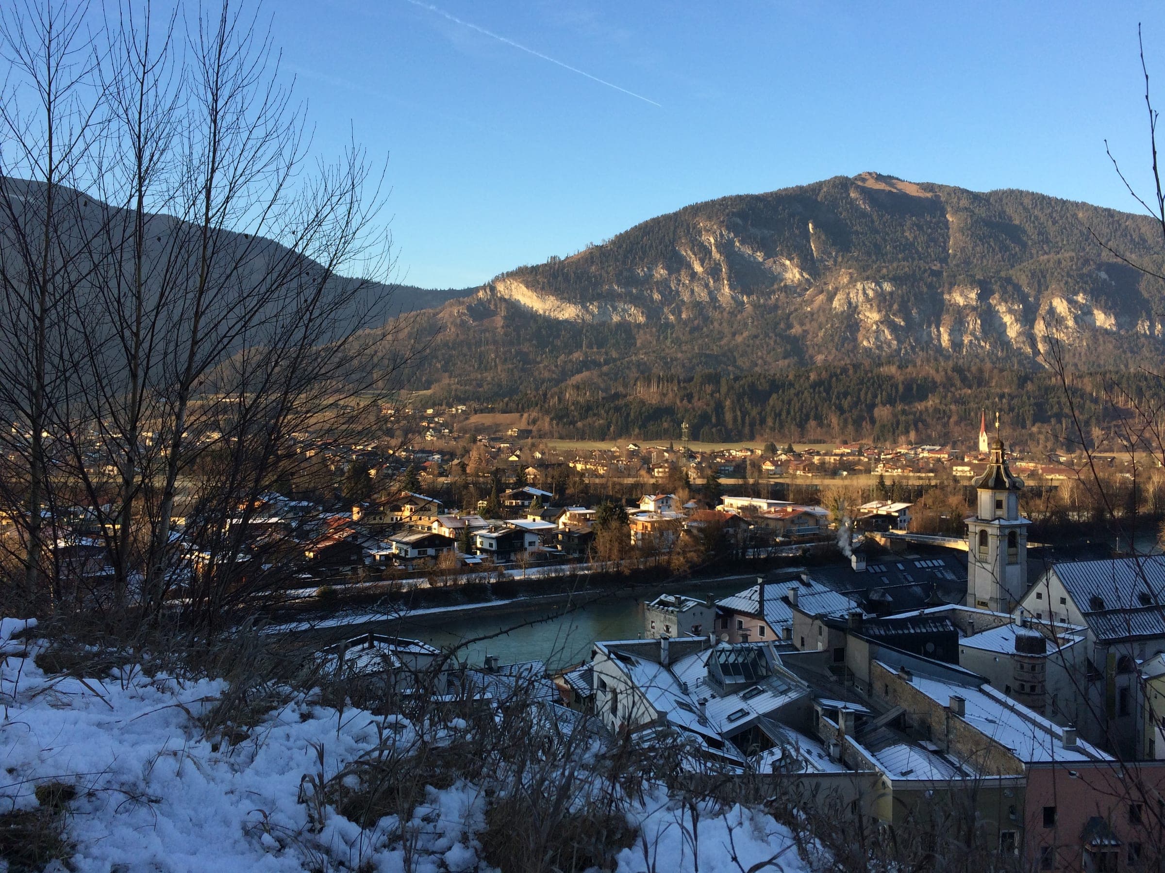 Rattenberg's old town lines the Inn under wooded mountains in a December view from the castle hill.