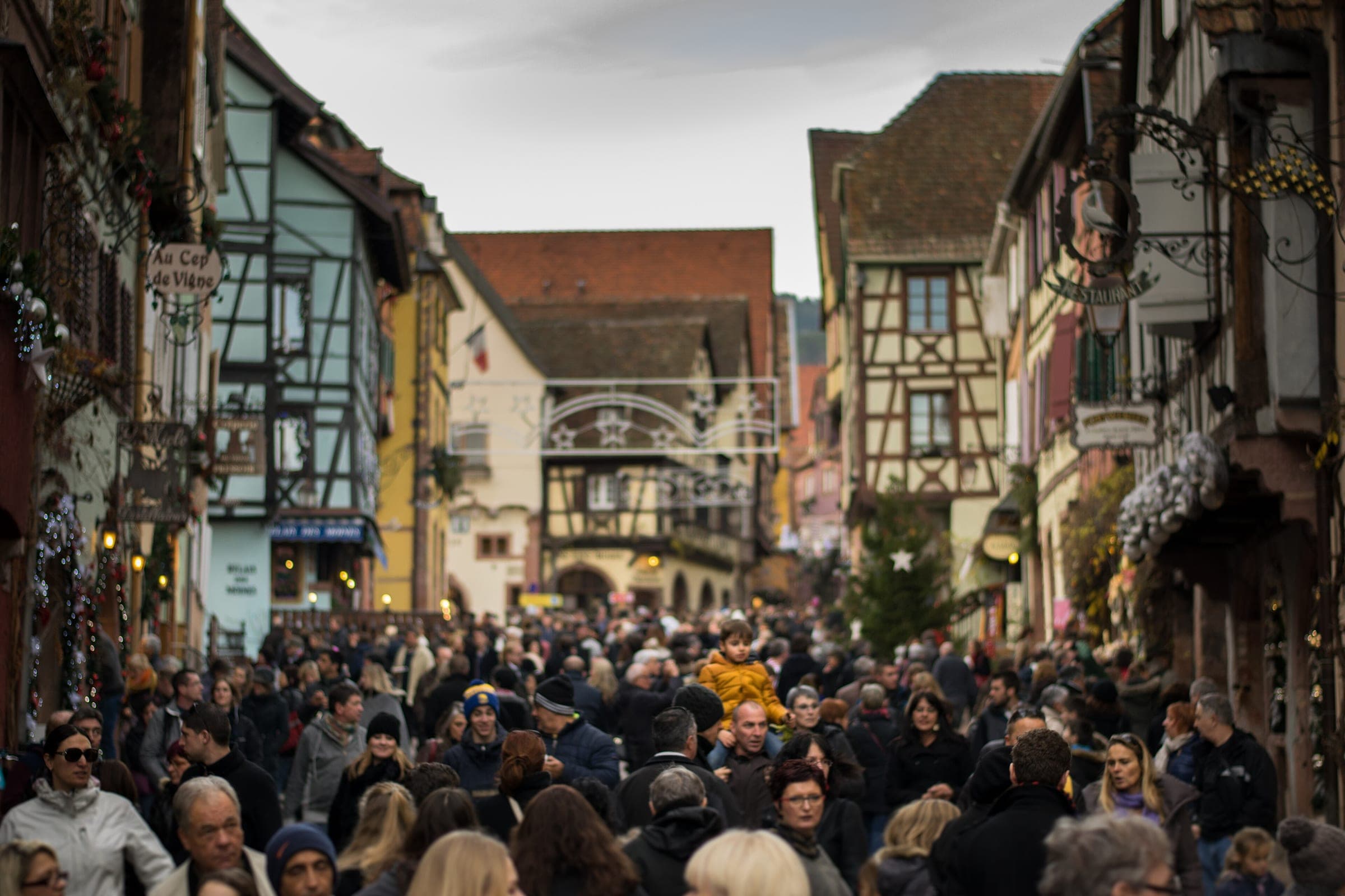 Crowds fill the main street of Riquewihr between half-timbered houses hung with Christmas decorations.