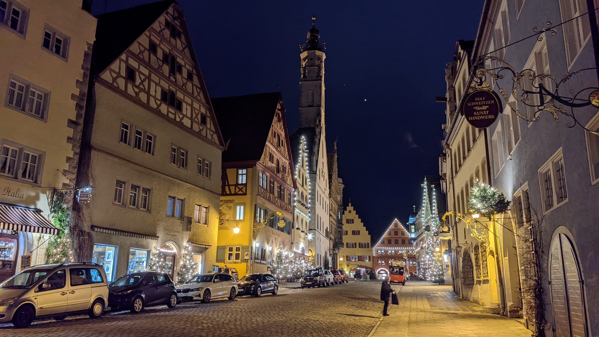 Lights hang over Herrngasse in Rothenburg ob der Tauber at night, with the Rathaus tower at the end of the street