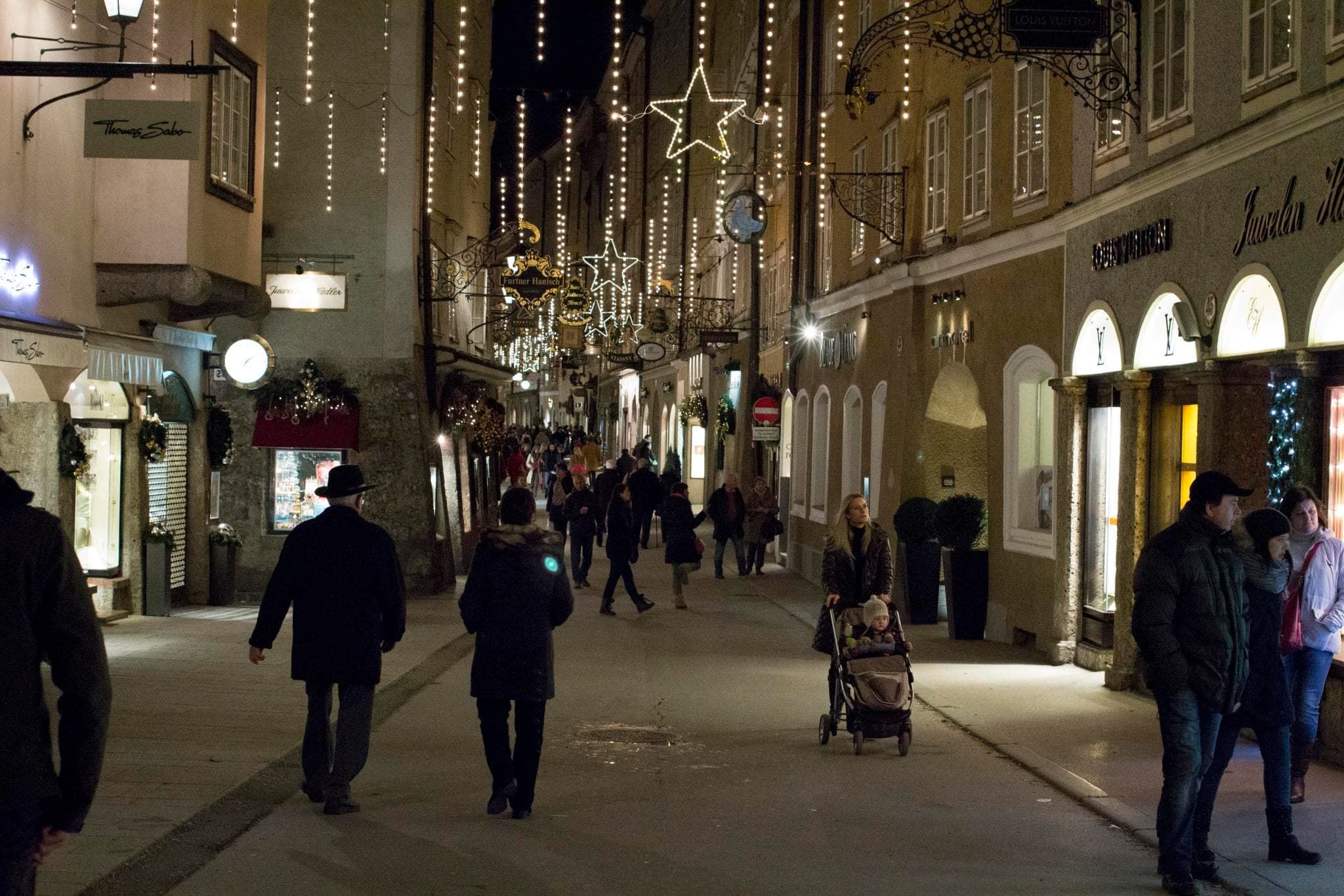 Star-shaped Christmas lights hang over shoppers in Salzburg's Getreidegasse at night