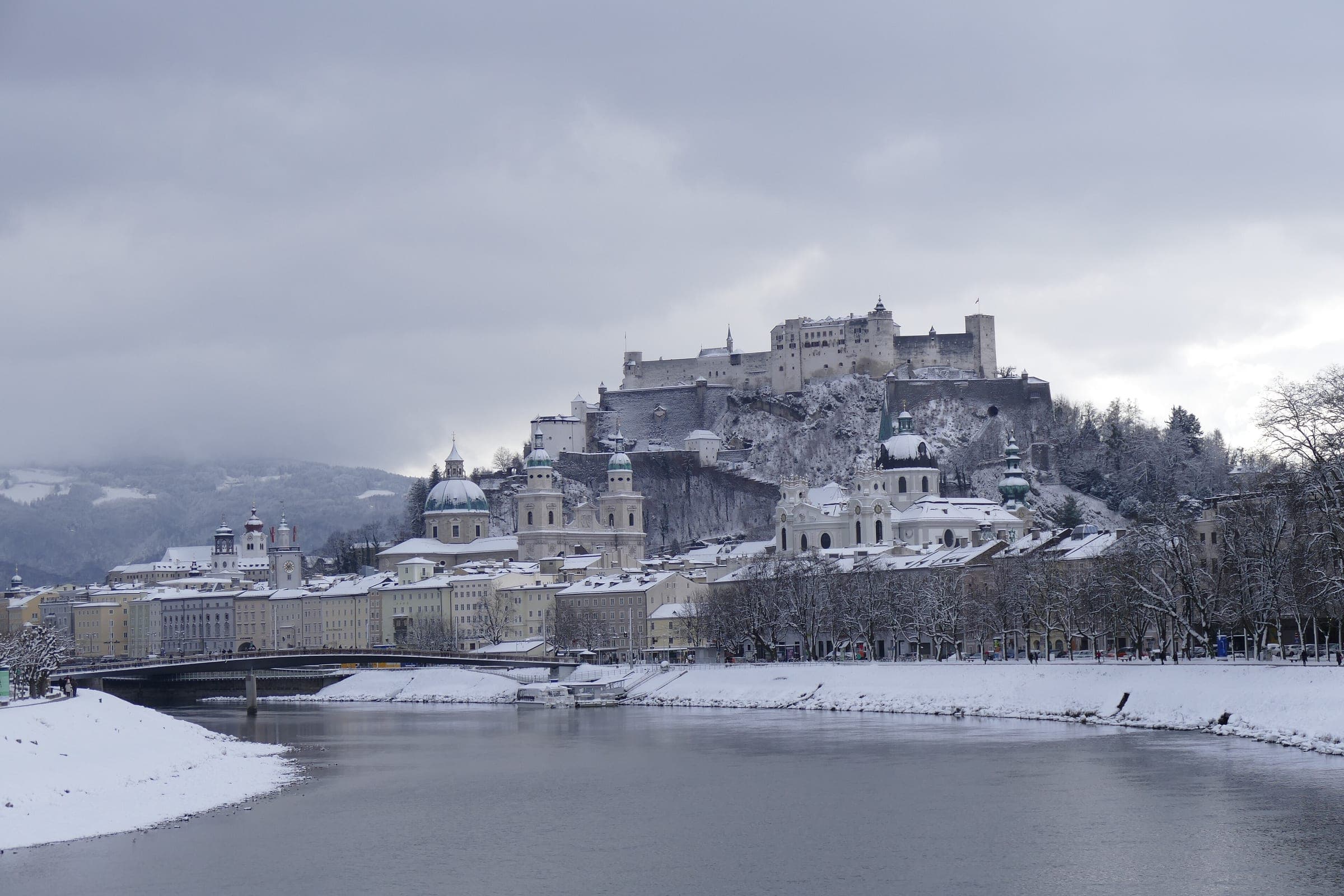 Snow lines the Salzach below Salzburg's old town domes and Hohensalzburg Fortress