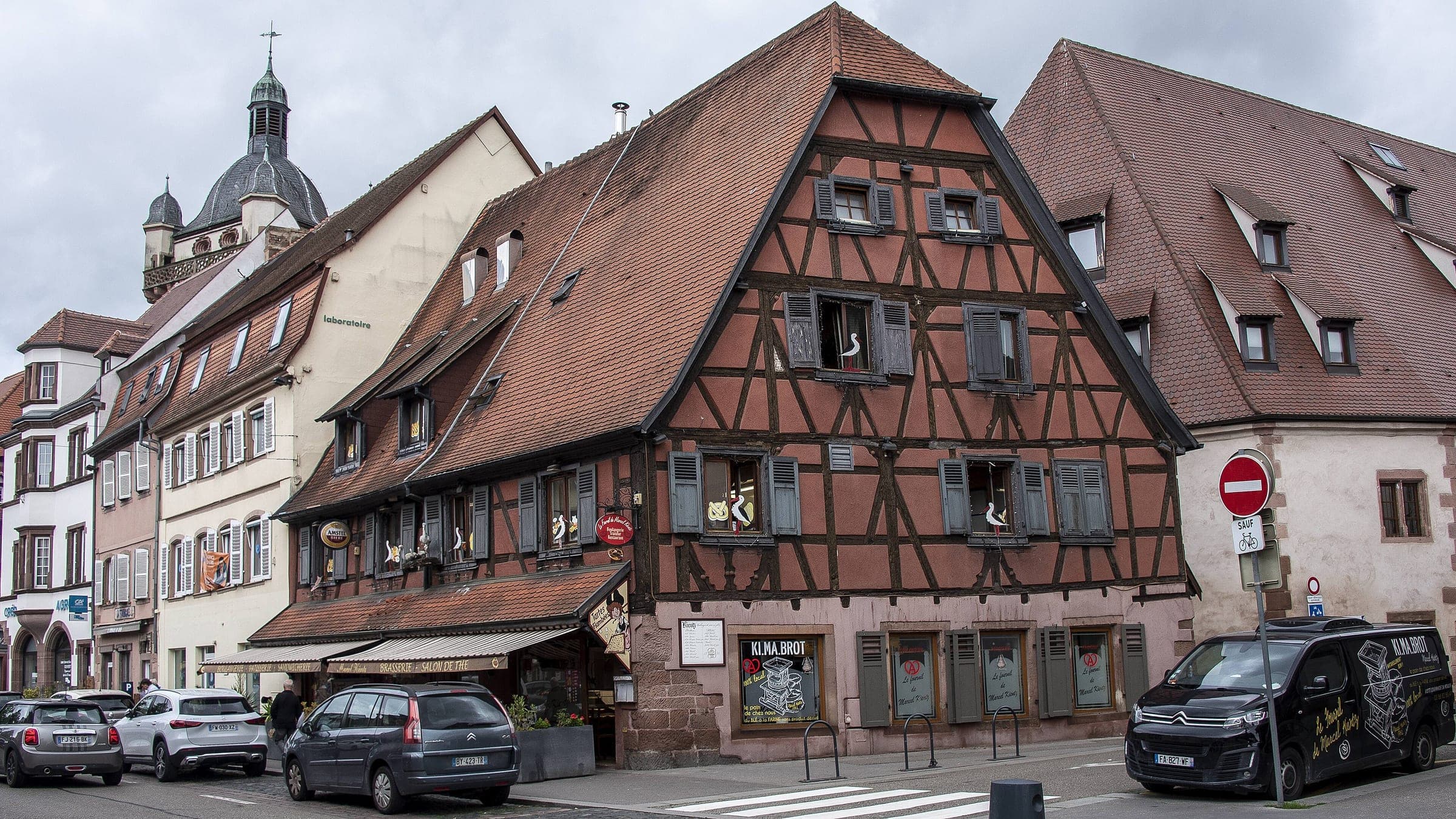 A large half-timbered house with a steep tiled roof stands on a street corner in old Sélestat.