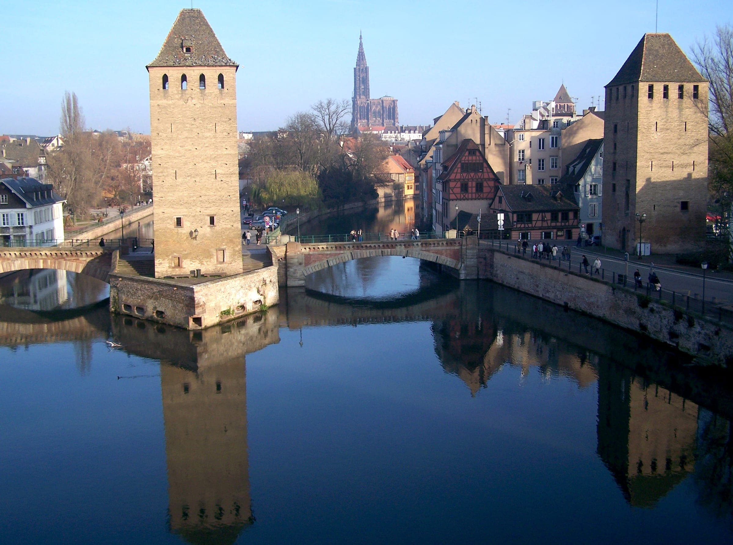 The towers of the Ponts Couverts stand in the Ill under a clear December sky with the cathedral spire beyond.