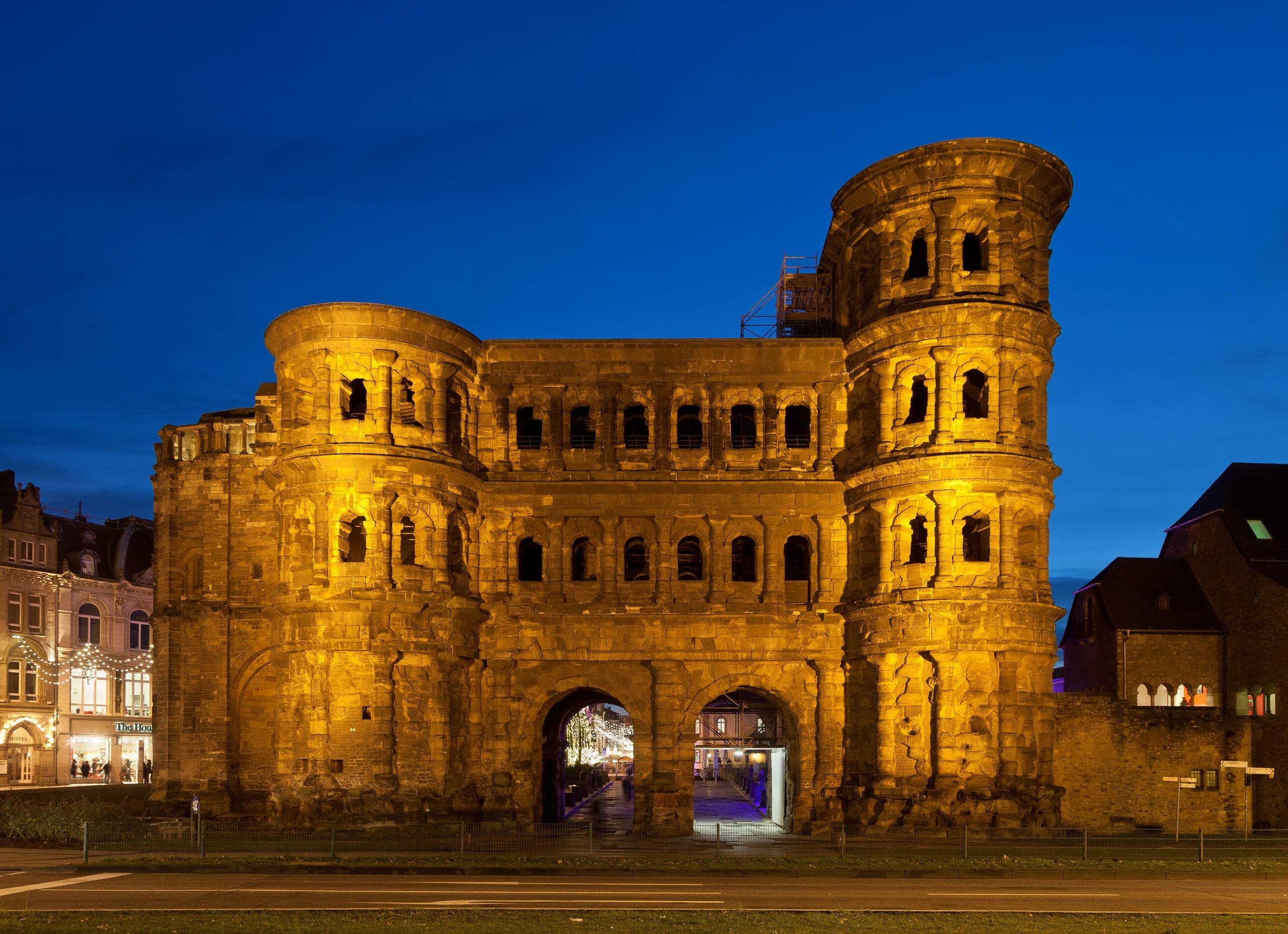 Floodlights turn the Roman Porta Nigra in Trier gold against a deep blue evening sky