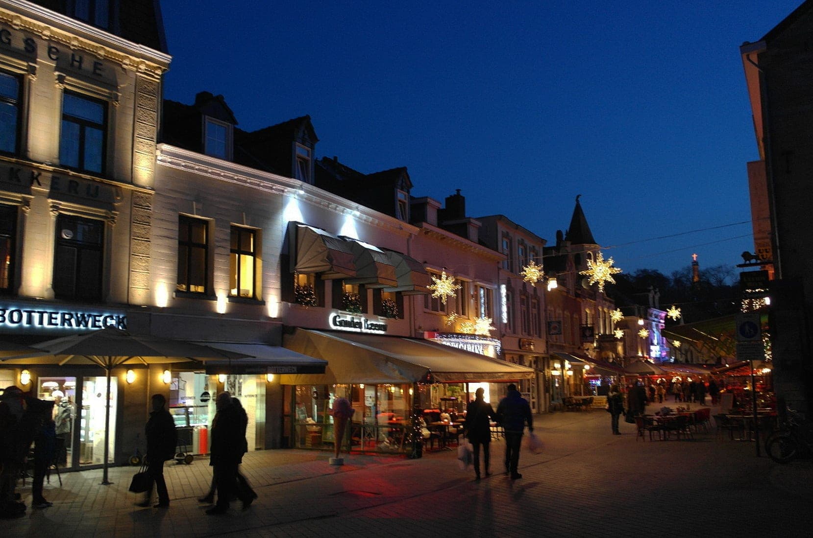 Star lights hang over Grotestraat in Valkenburg as the shopfronts glow at blue hour.