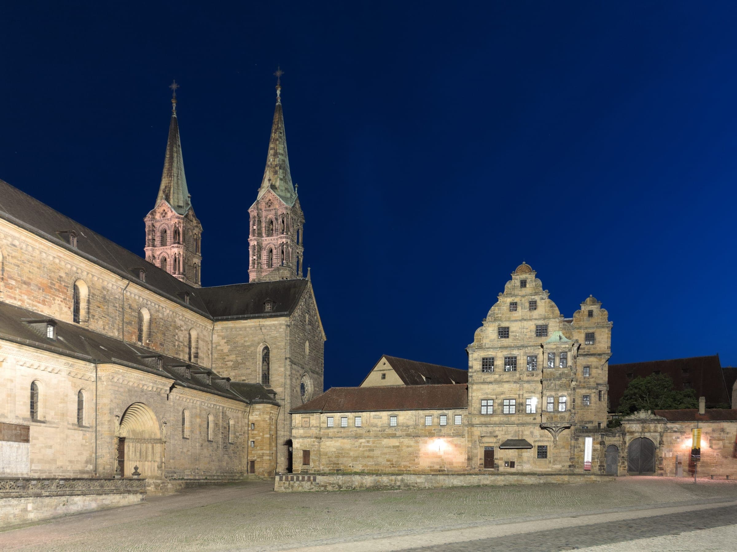 Bamberg Cathedral and the Alte Hofhaltung stand floodlit around the empty Domplatz at night