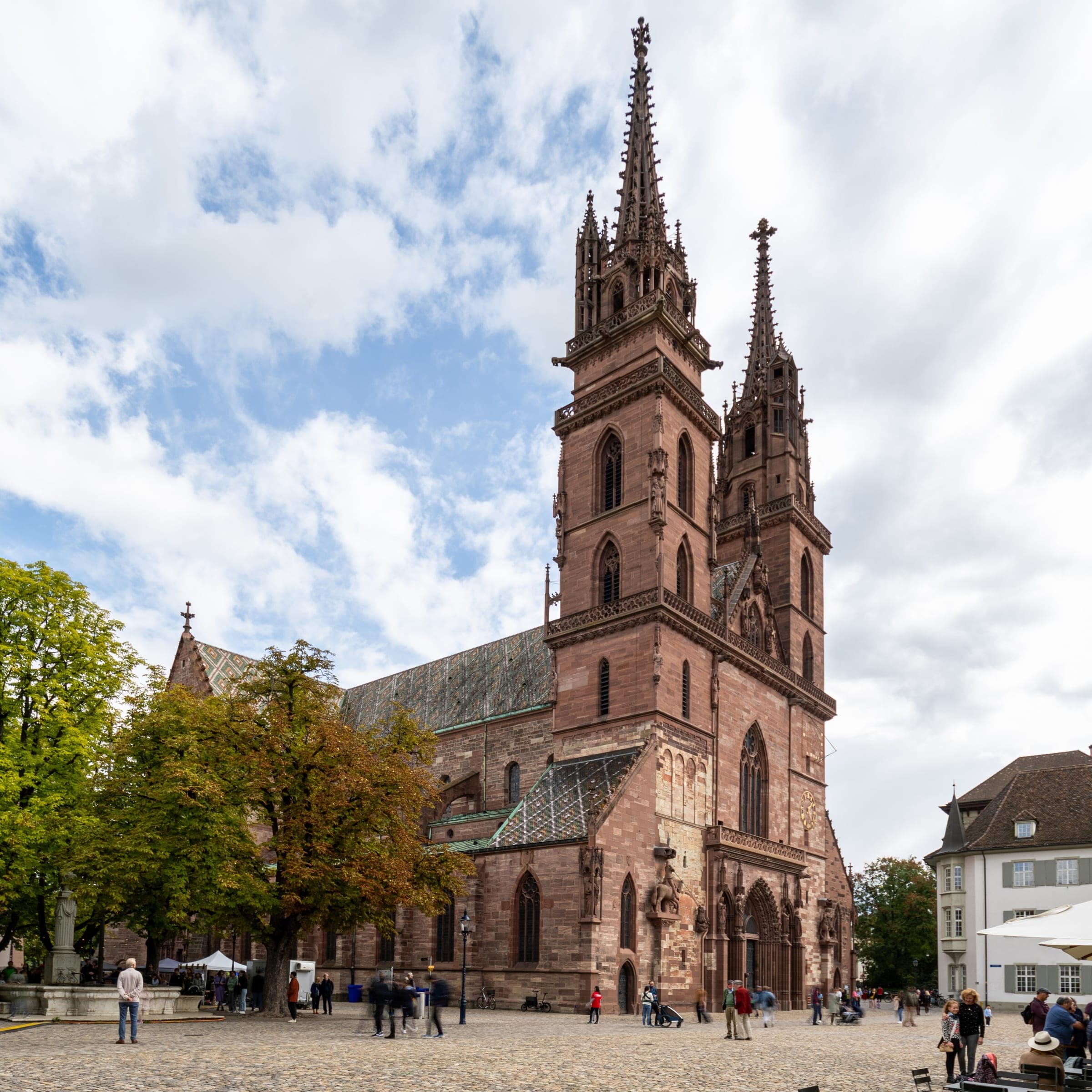 The red sandstone towers of Basel Minster stand over Münsterplatz and its trees