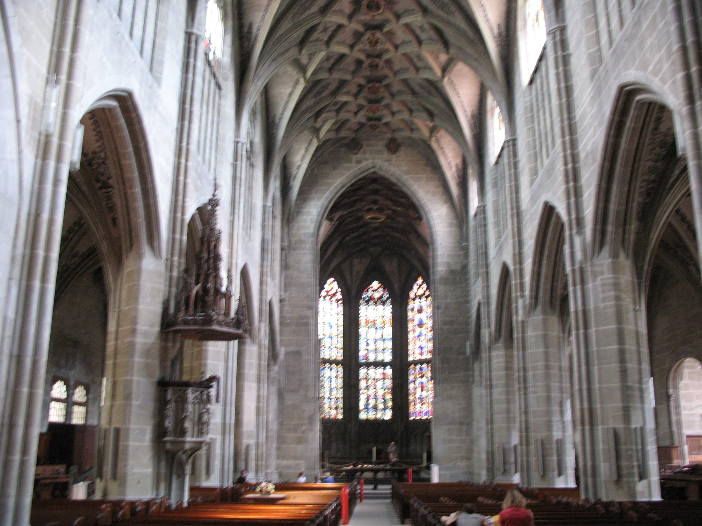 The nave of Bern Minster leads under a ribbed vault to the stained glass of the choir