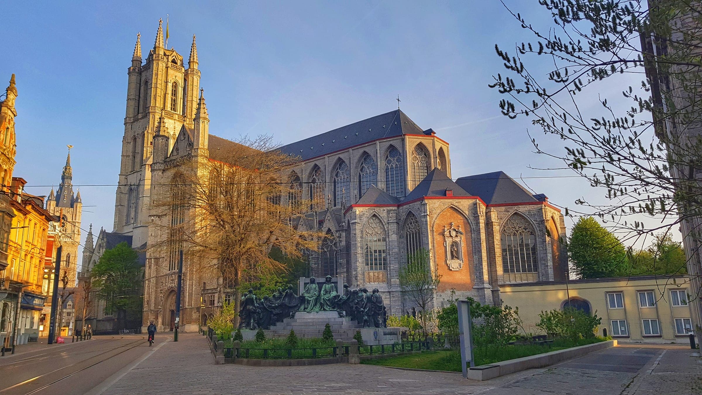 Morning sun warms the tower and chapels of St Bavo's Cathedral on the Sint-Baafsplein in Ghent.