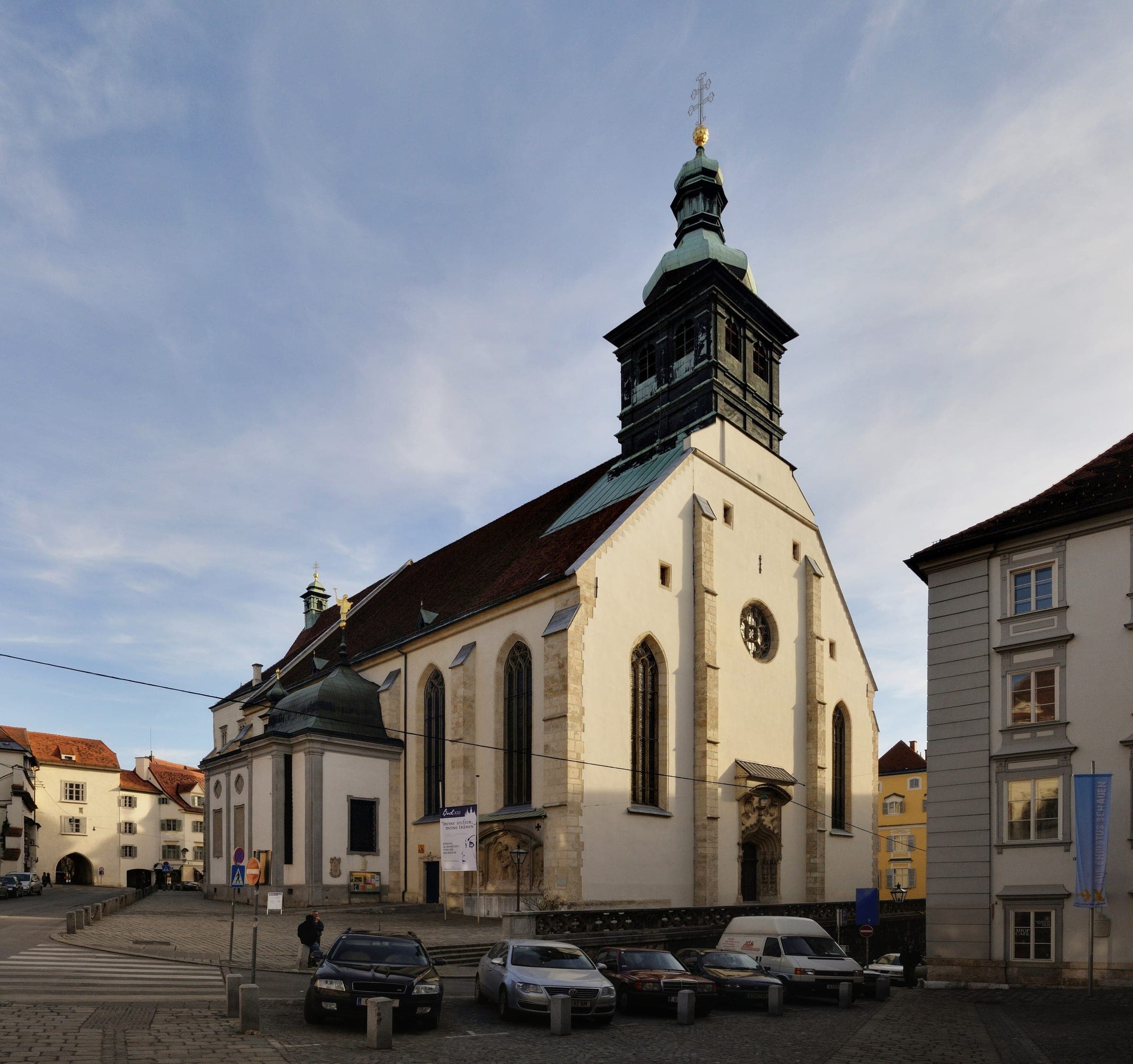 The white Gothic Graz Cathedral and its green-capped tower stand on Bürgergasse in January light.