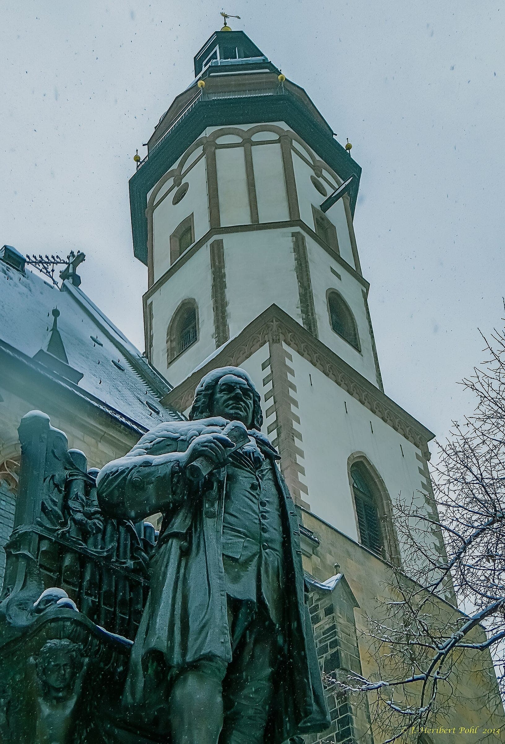Snow falls on the Bach statue below the tower of the Thomaskirche in Leipzig.