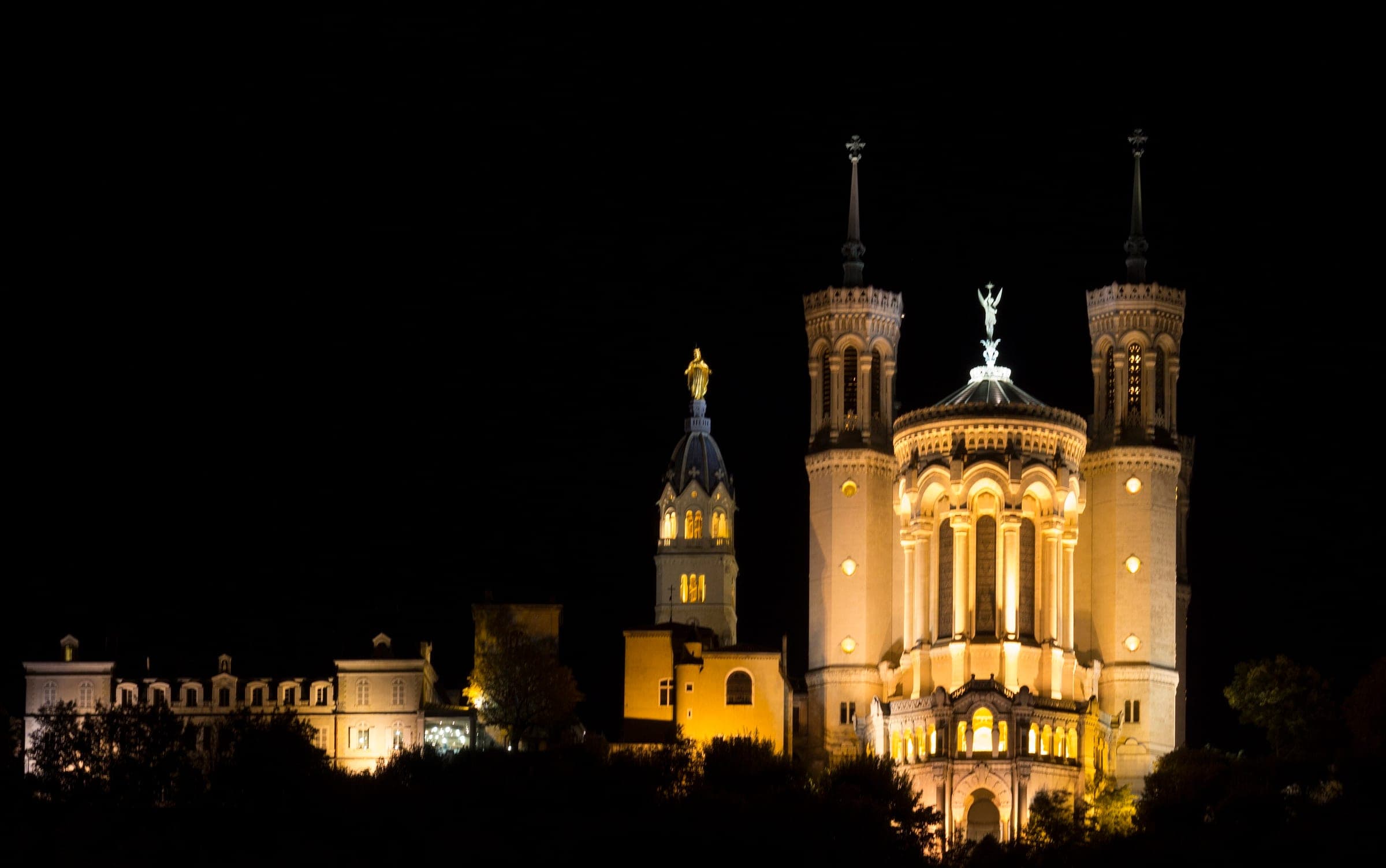 Floodlights pick out the towers and gilded Virgin of Notre-Dame de Fourvière above Lyon at night.