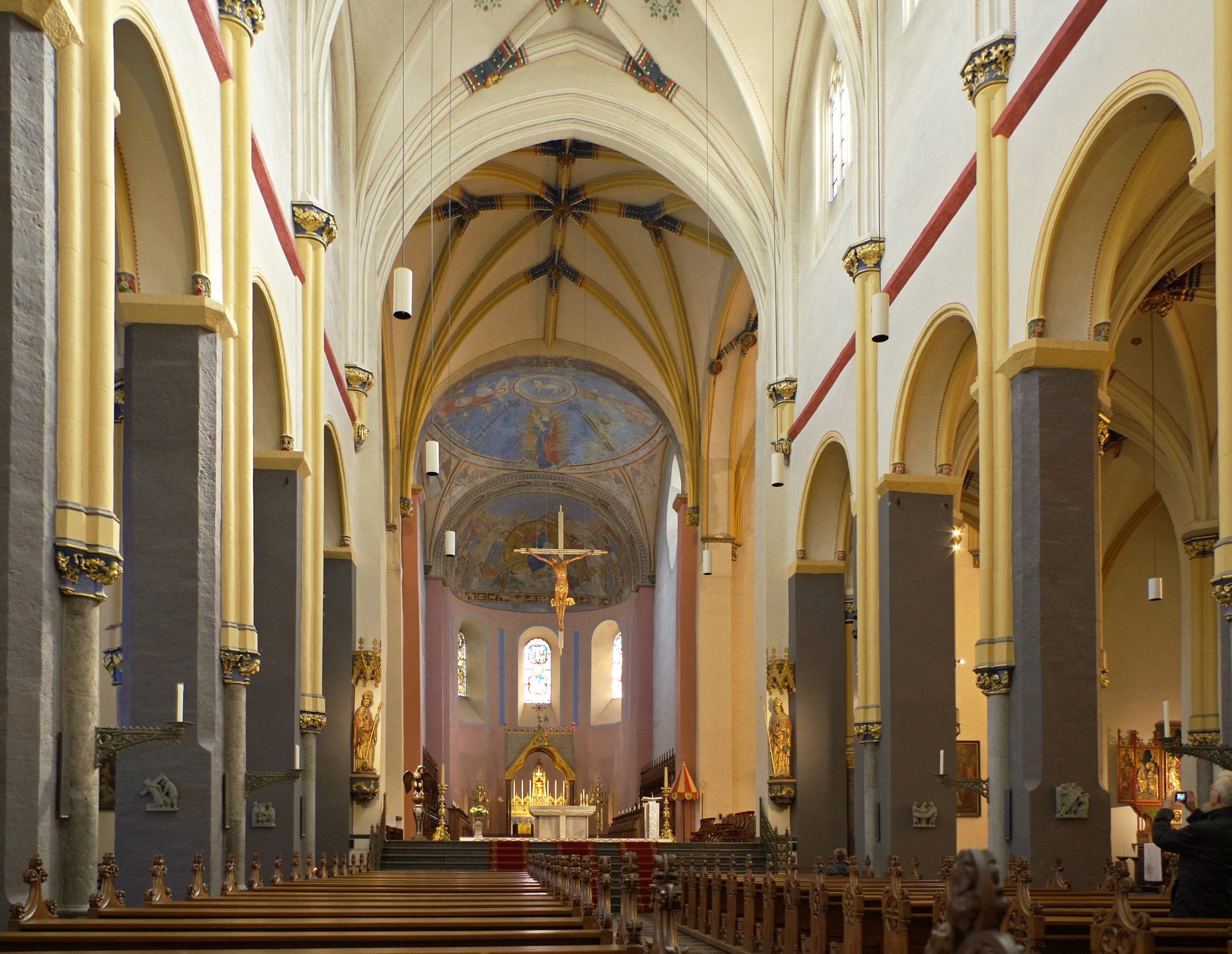 Rows of pews lead down the pale Gothic nave of the Basilica of Saint Servatius in Maastricht to the painted apse.