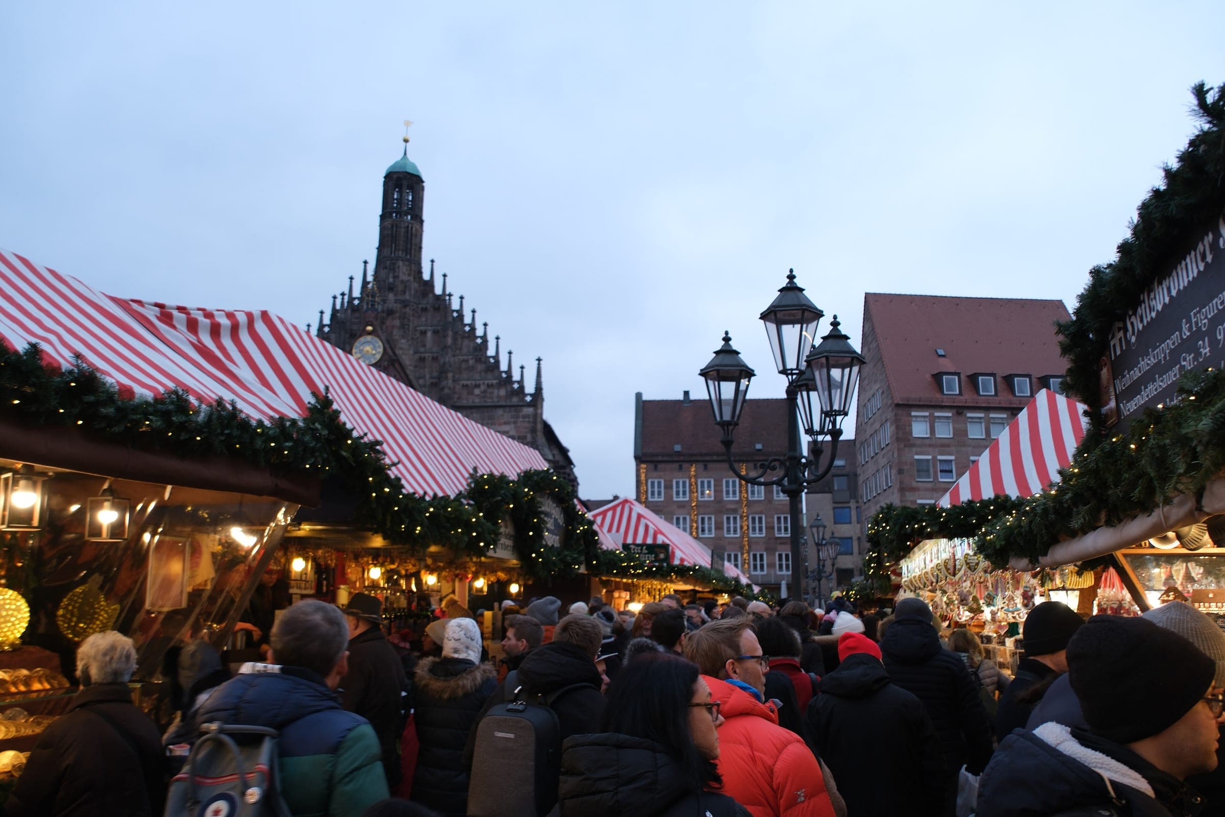 The Frauenkirche rises over the striped stall roofs and evening crowd of Nuremberg's Christkindlesmarkt