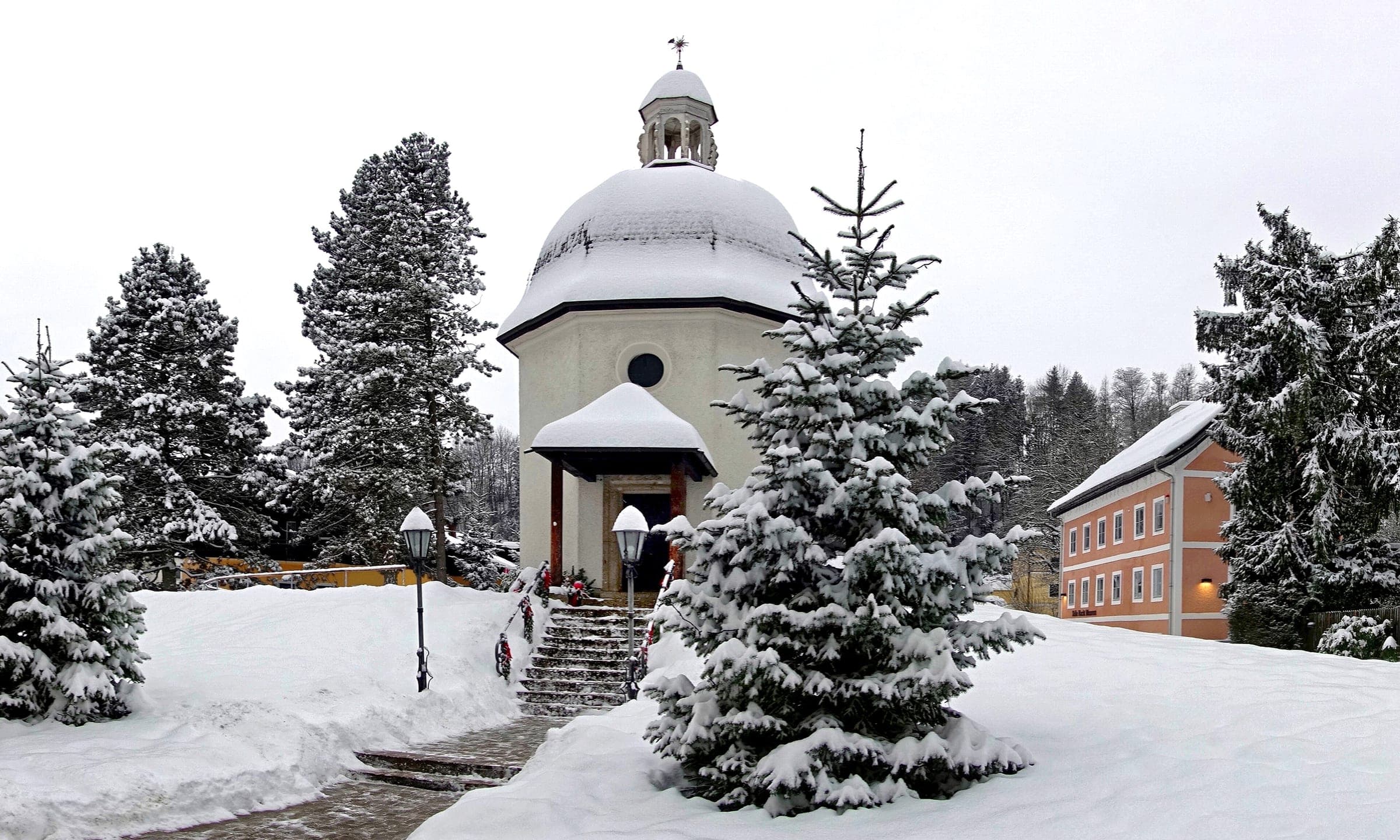 Snow-laden firs surround the Silent Night Chapel in Oberndorf bei Salzburg