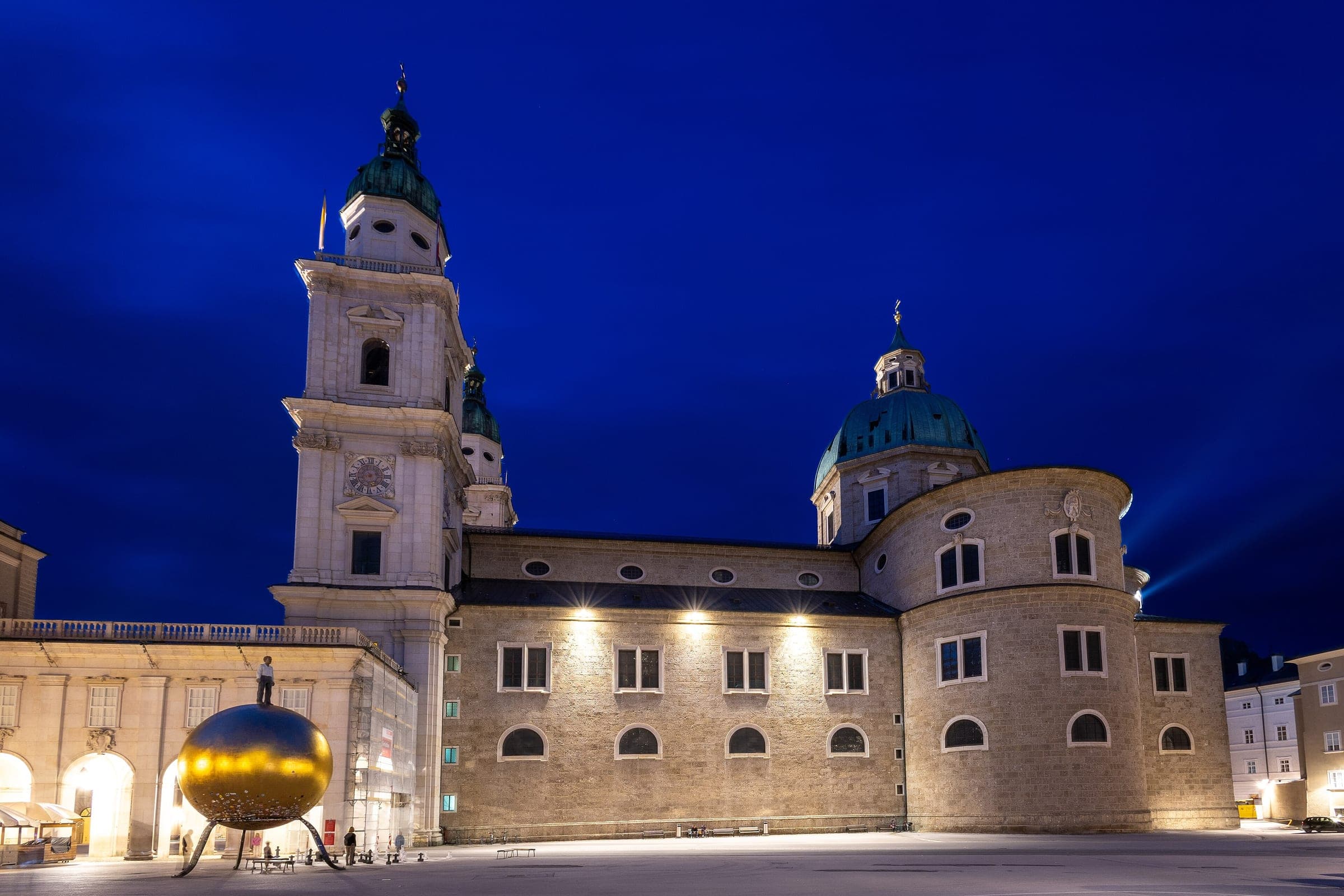 Salzburg Cathedral's floodlit towers and dome rise over the Kapitelplatz at blue hour