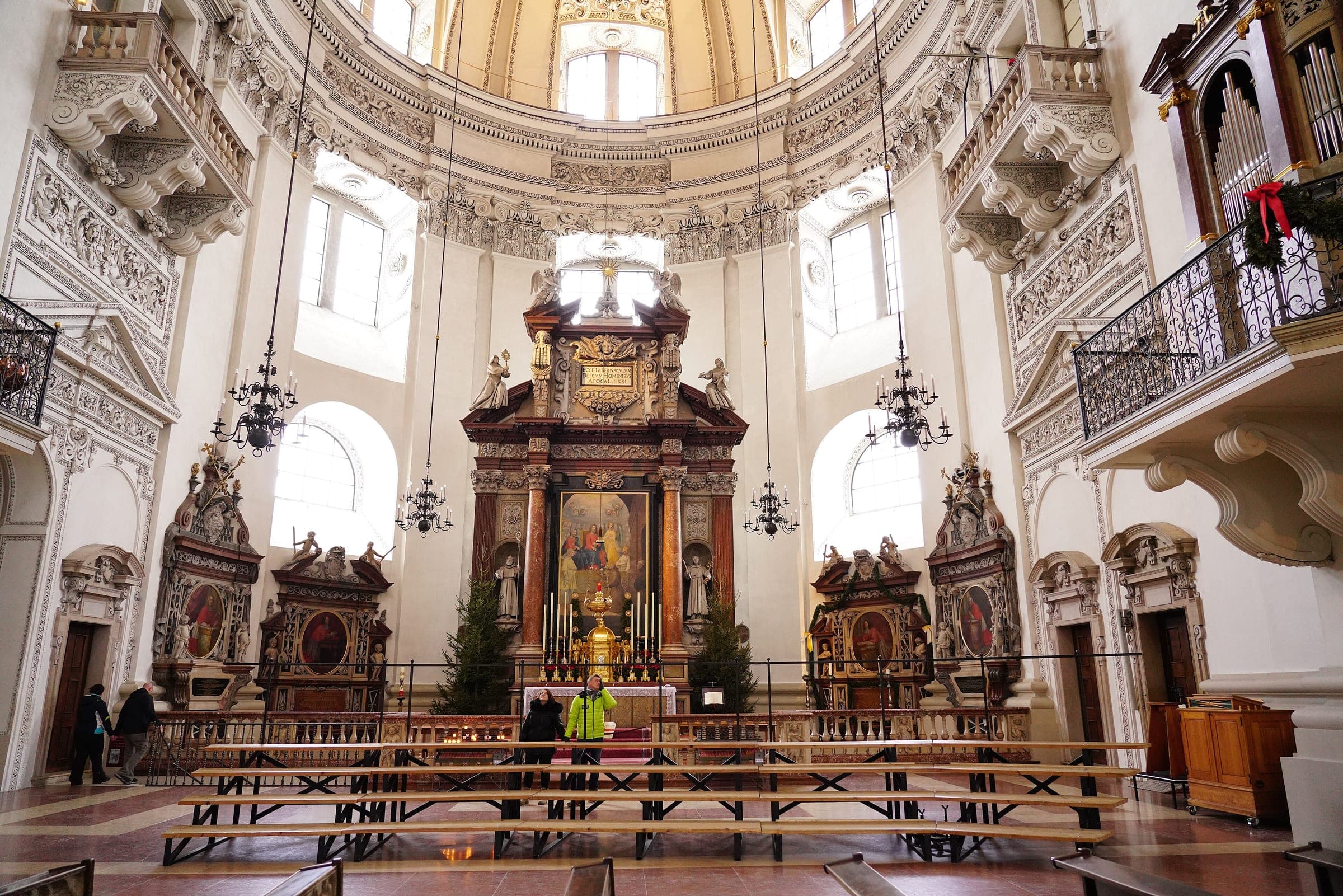 Christmas trees flank the high altar beneath the white stucco crossing of Salzburg Cathedral