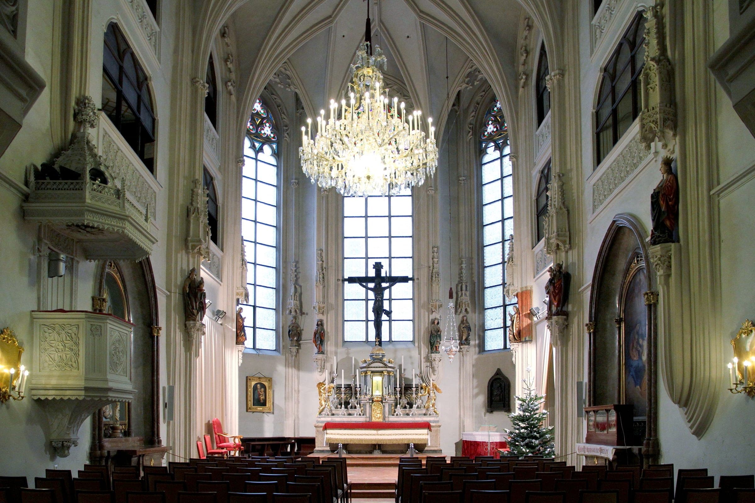 A Christmas tree stands by the altar of the empty Hofburg Chapel in Vienna below its crystal chandelier.