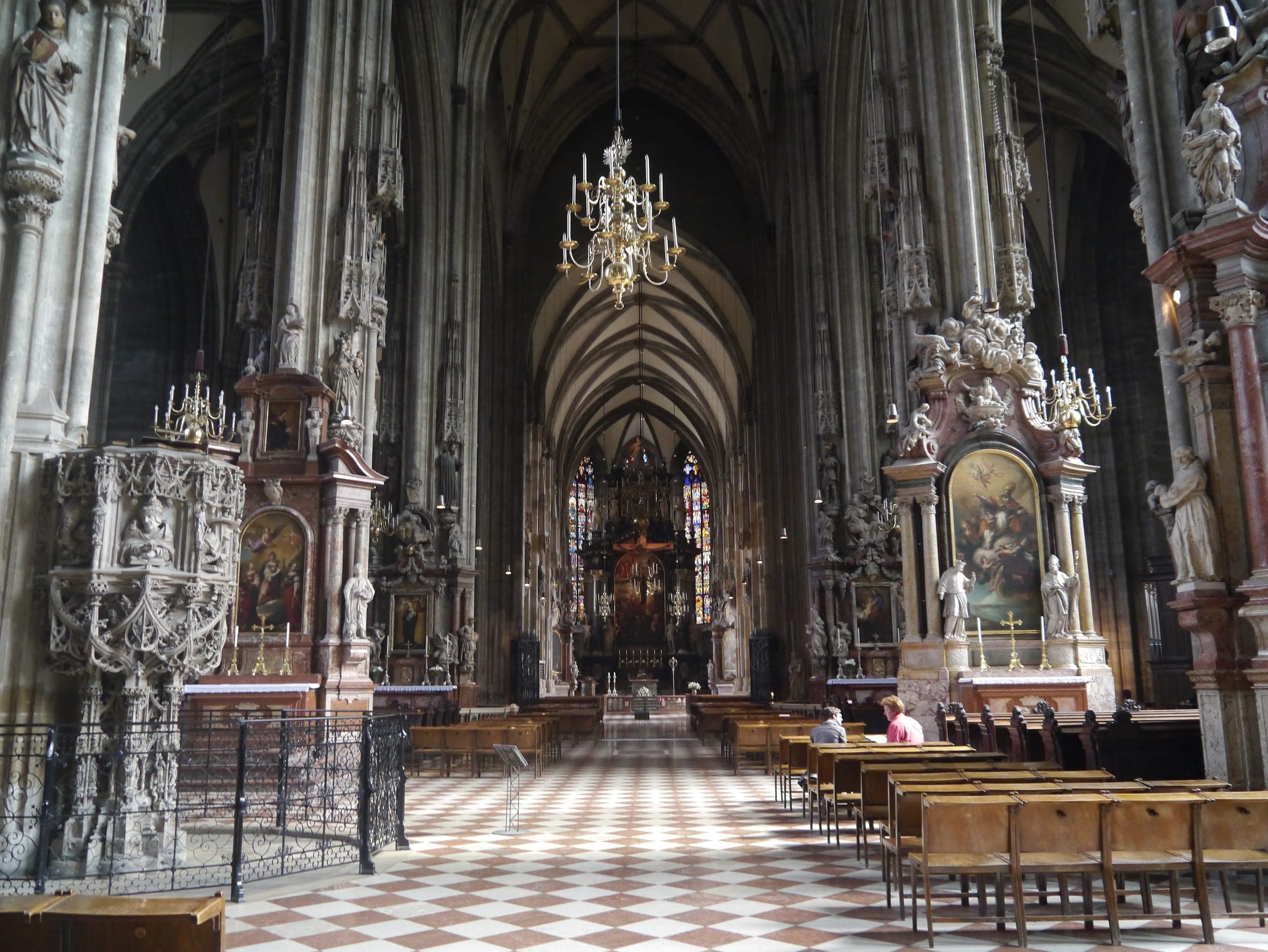 Chandeliers hang down the Gothic nave of St. Stephen's Cathedral in Vienna above its chequered floor.