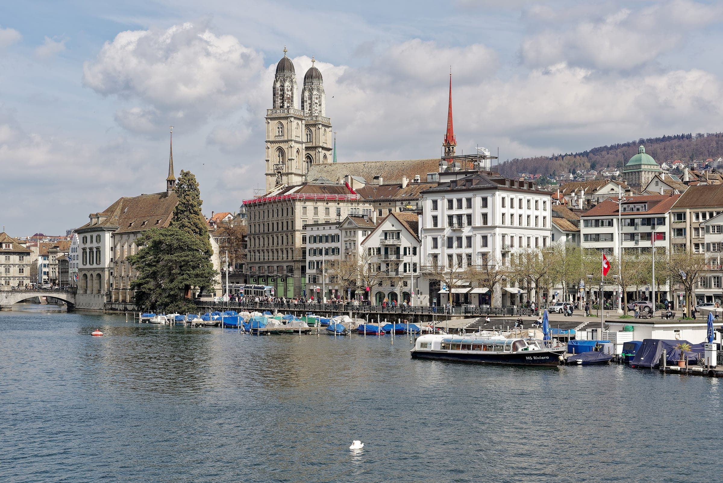 The Grossmünster stands above the houses and boats of the Limmatquai in Zurich